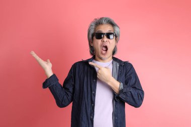 Pembe arka planda duran Asyalı adam..