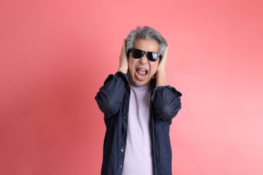 Pembe arka planda duran Asyalı adam..