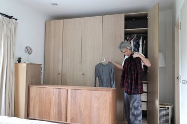 Üst düzey Asyalı adam yatak odasında kıyafet seçiyor..