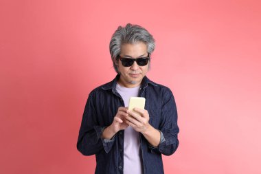 Pembe arka planda duran Asyalı adam..