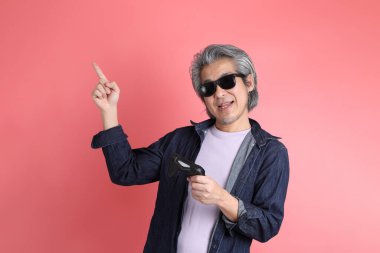 Pembe arka planda duran Asyalı adam..