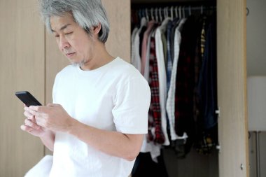 Odada akıllı telefon kullanan Asyalı adam..