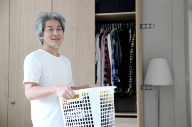 Çamaşır yıkamak için çamaşır sepeti taşıyan Asyalı adam..