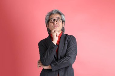 Pembe arka planda duran Asyalı adam..