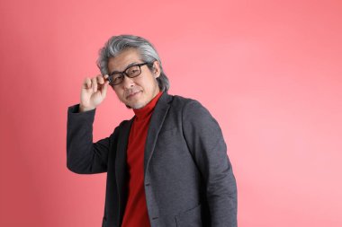 Pembe arka planda duran Asyalı adam..