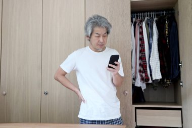 Odada akıllı telefon kullanan Asyalı adam..