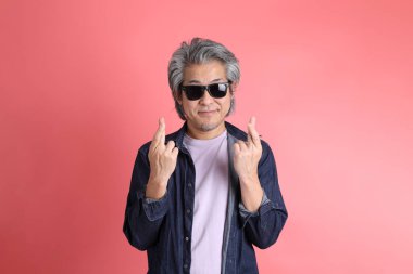 Pembe arka planda duran Asyalı adam..