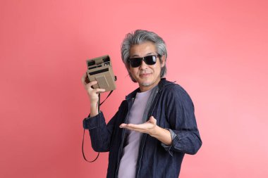 Pembe arka planda duran Asyalı adam..