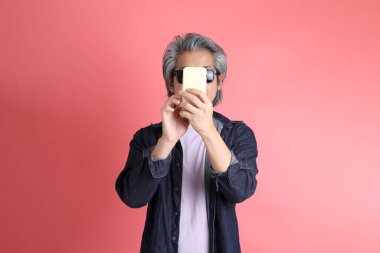 Pembe arka planda duran Asyalı adam..