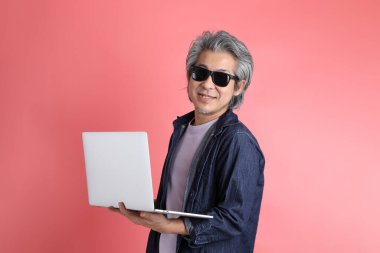 Pembe arka planda duran Asyalı adam..