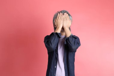 Pembe arka planda duran Asyalı adam..