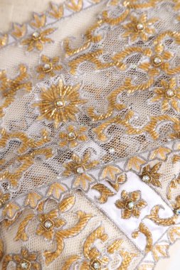 Dişi mankenin üzerine sarılı Tayland altın dekoratif desenli pileli şal.