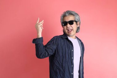 Pembe arka planda duran Asyalı adam..