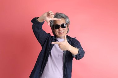 Pembe arka planda duran Asyalı adam..