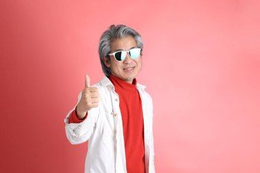 Pembe arka planda duran Asyalı adam..