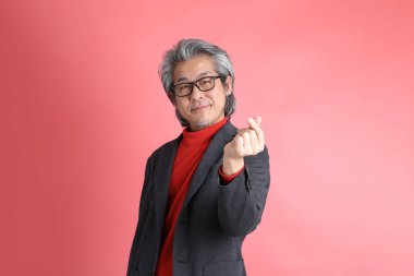 Pembe arka planda duran Asyalı adam..