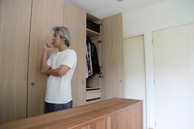 Üst düzey Asyalı adam yatak odasında kıyafet seçiyor..