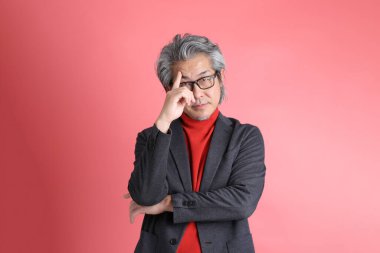 Pembe arka planda duran Asyalı adam..