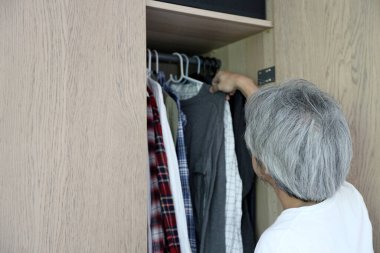 Üst düzey Asyalı adam yatak odasında kıyafet seçiyor..