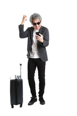 Beyaz arka planda bagajı olan kıdemli Asyalı işadamı..