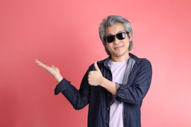 Pembe arka planda duran Asyalı adam..