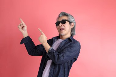 Pembe arka planda duran Asyalı adam..