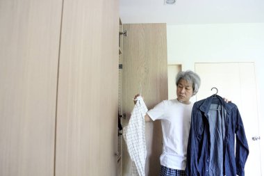 Üst düzey Asyalı adam yatak odasında kıyafet seçiyor..