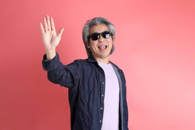 Pembe arka planda duran Asyalı adam..