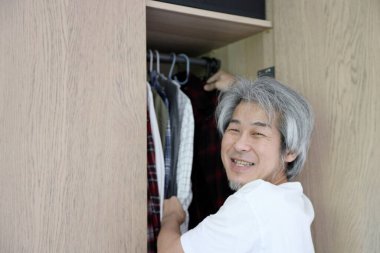 Üst düzey Asyalı adam yatak odasında kıyafet seçiyor..