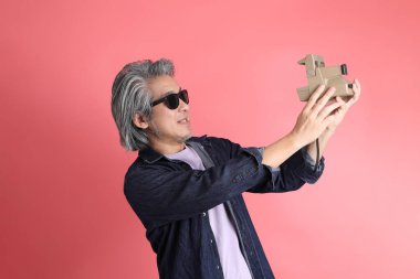 Pembe arka planda duran Asyalı adam..