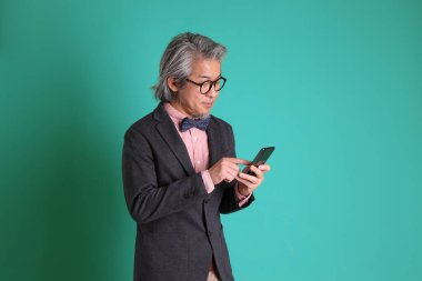 Yeşil arka planda duran kıdemli Asyalı öğretmen..