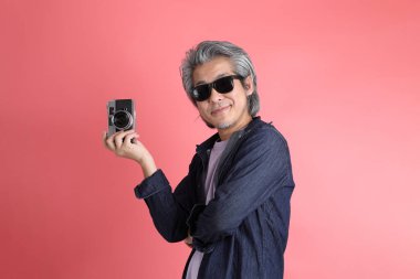 Pembe arka planda duran Asyalı adam..