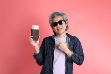 Pembe arka planda duran Asyalı adam..