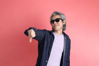 Pembe arka planda duran Asyalı adam..