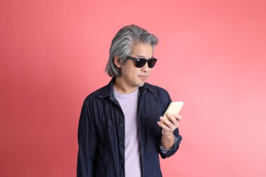 Pembe arka planda duran Asyalı adam..