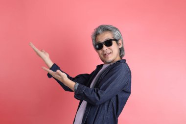 Pembe arka planda duran Asyalı adam..