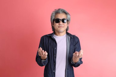 Pembe arka planda duran Asyalı adam..