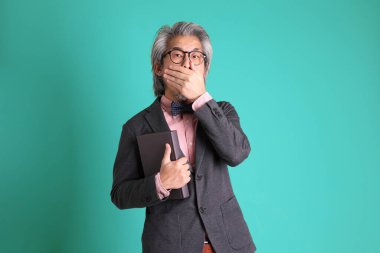 Yeşil arka planda duran kıdemli Asyalı öğretmen..