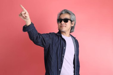 Pembe arka planda duran Asyalı adam..