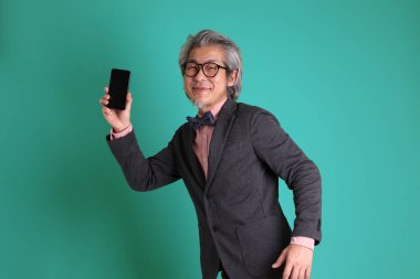 Yeşil arka planda duran kıdemli Asyalı öğretmen..