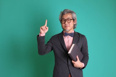 Yeşil arka planda duran kıdemli Asyalı öğretmen..