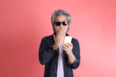 Pembe arka planda duran Asyalı adam..