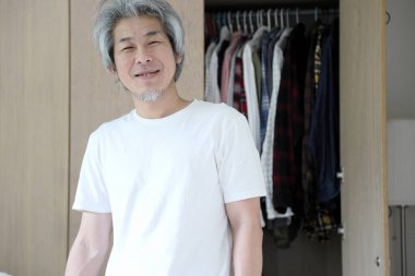 Üst düzey Asyalı adam yatak odasında kıyafet seçiyor..