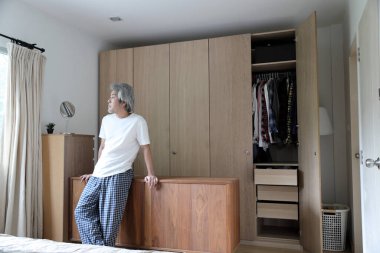 Asyalı adam yatak odasında duruyor..