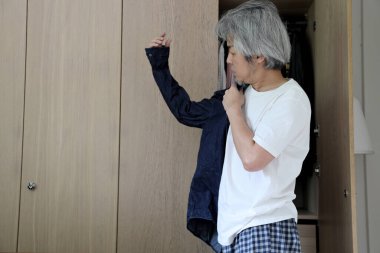 Üst düzey Asyalı adam yatak odasında kıyafet seçiyor..