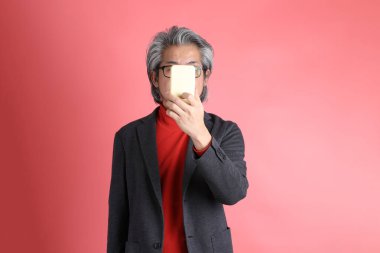 Pembe arka planda duran Asyalı adam..