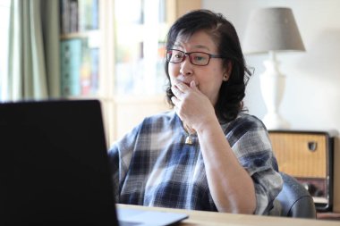 Dizüstü bilgisayar kullanan yaşlı Asyalı kadın..