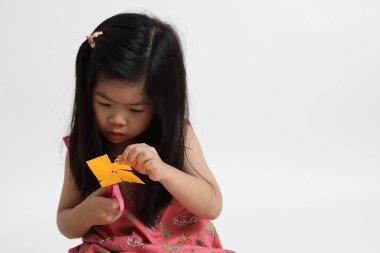 Kağıdı kesmek için makas kullanan Asyalı kız..