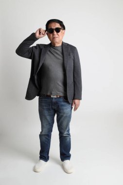 Beyaz arka planda güneş gözlüklü Asyalı son sınıf öğrencisi..