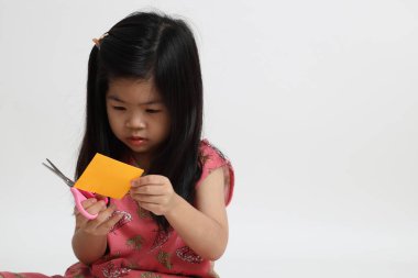 Kağıdı kesmek için makas kullanan Asyalı kız..